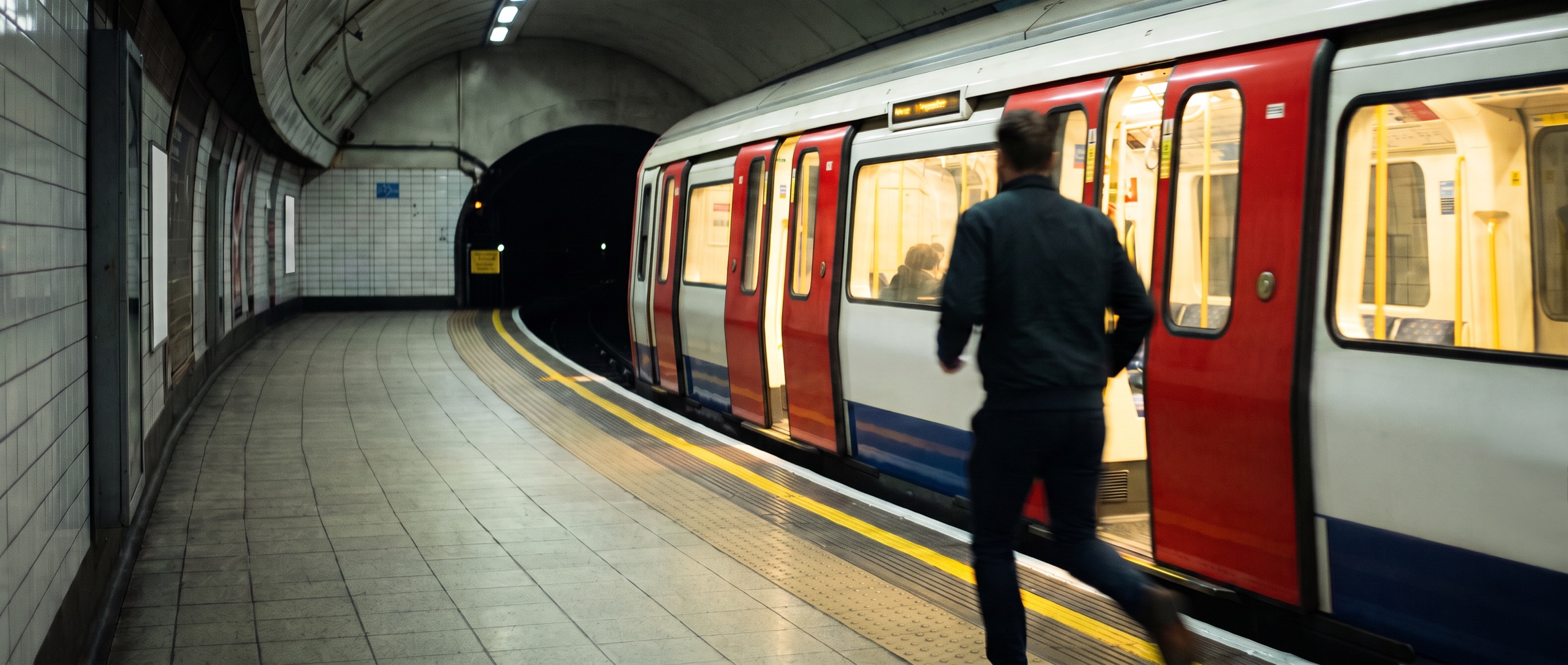 A person running along an underground platform for a train as its doors close